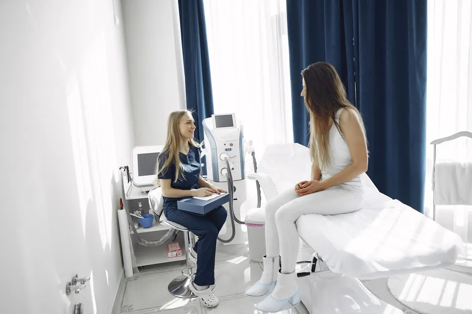 Clinician talking with a patient seated on a treatment bed before an aesthetic procedure