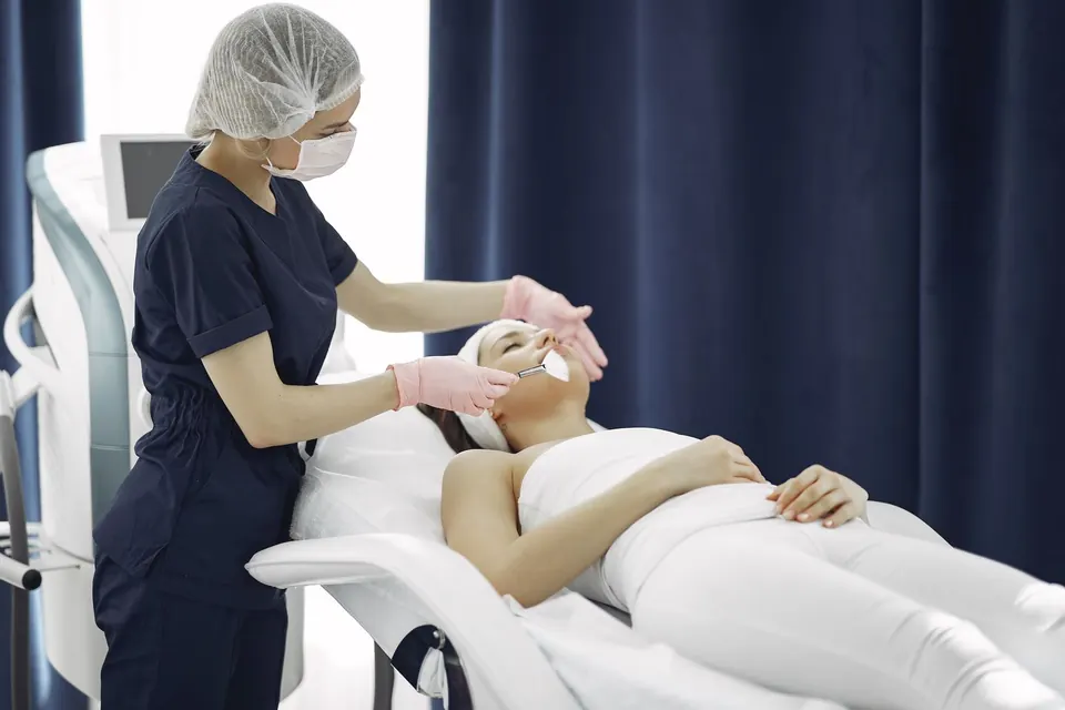 Aesthetic clinician in scrubs preparing a patient lying on a treatment chair