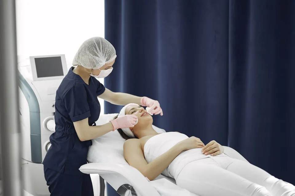 Clinician preparing a patient on a treatment bed in an aesthetic clinic room