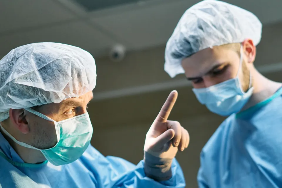 Two surgeons in caps and masks talking in an operating theatre