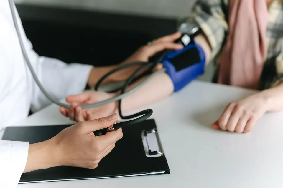 Clinician measuring a patient's blood pressure at a desk