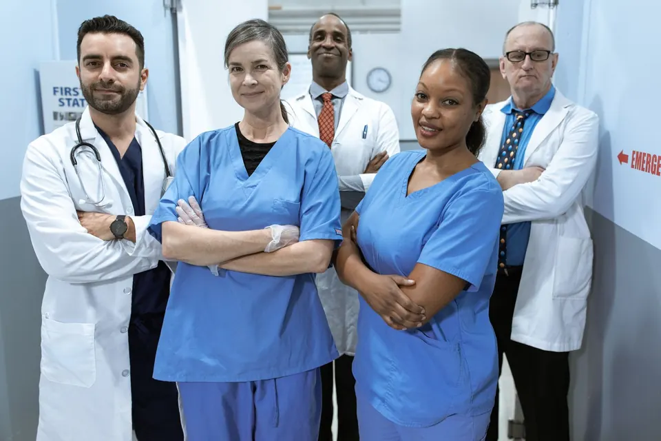 Team of doctors and nurses standing together in a clinic corridor