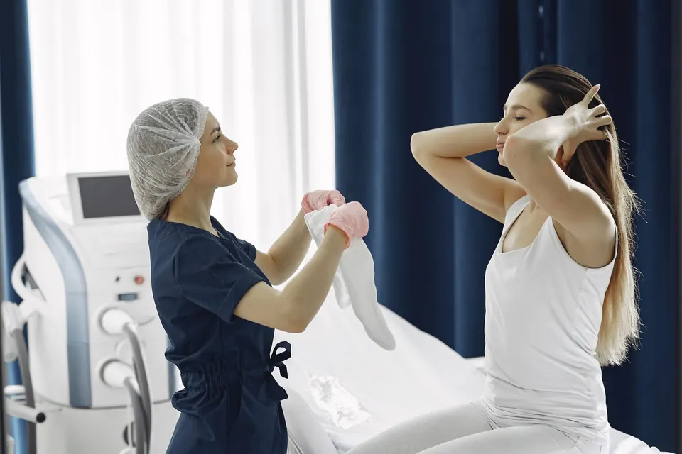 Clinician preparing a seated patient in a treatment room with an aesthetic device in the background