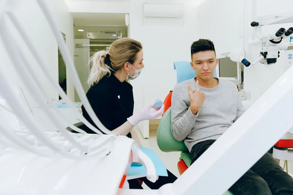Dentist explaining a treatment plan to a seated patient in a bright dental clinic