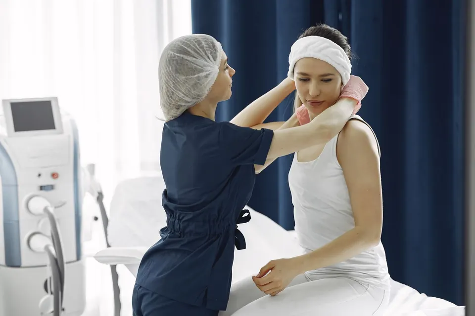 Clinician preparing a patient beside a skin treatment device in a bright aesthetic clinic room