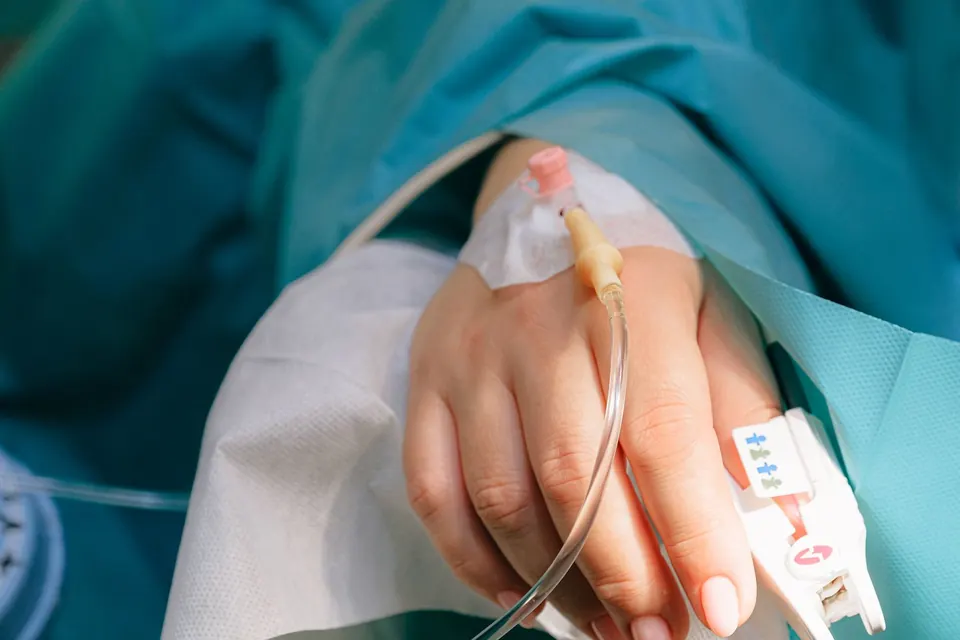 Close-up of an IV line taped to a patient's hand in a clinic