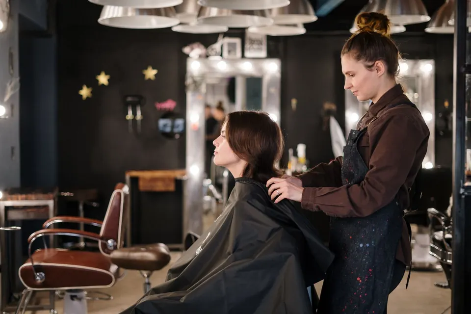 Hairdresser placing a cape on a customer before a treatment in a modern salon