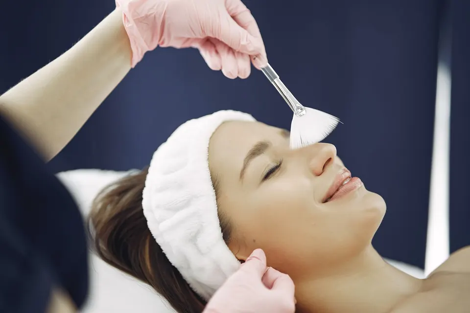 Clinician applying a skin treatment with a brush to a patient lying on a treatment bed