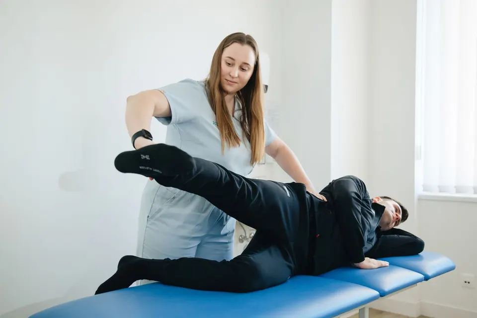 Physiotherapist guiding a patient's leg stretch on a treatment table