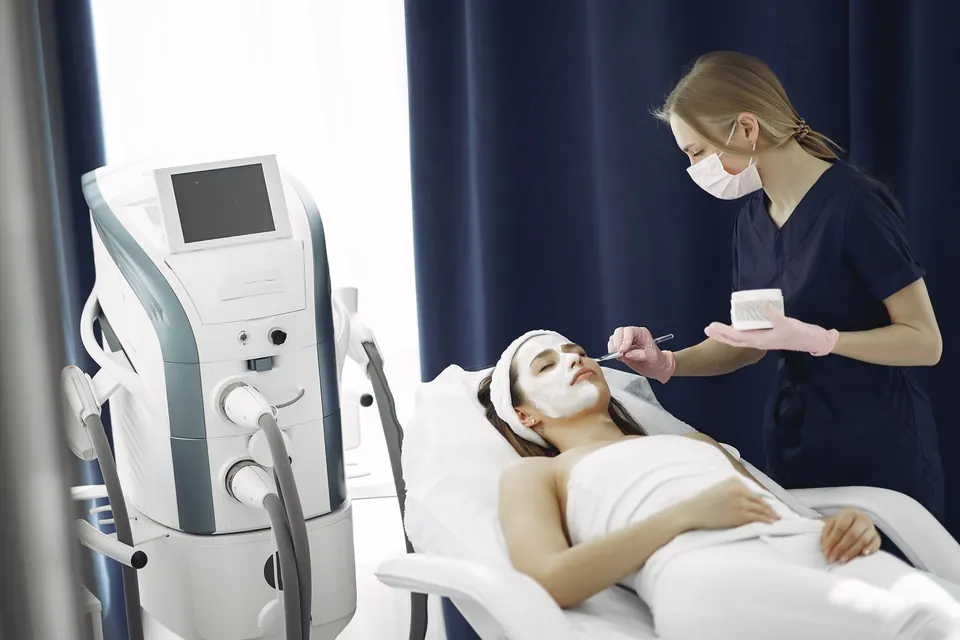 Clinician preparing a patient's skin on a treatment bed next to a laser platform