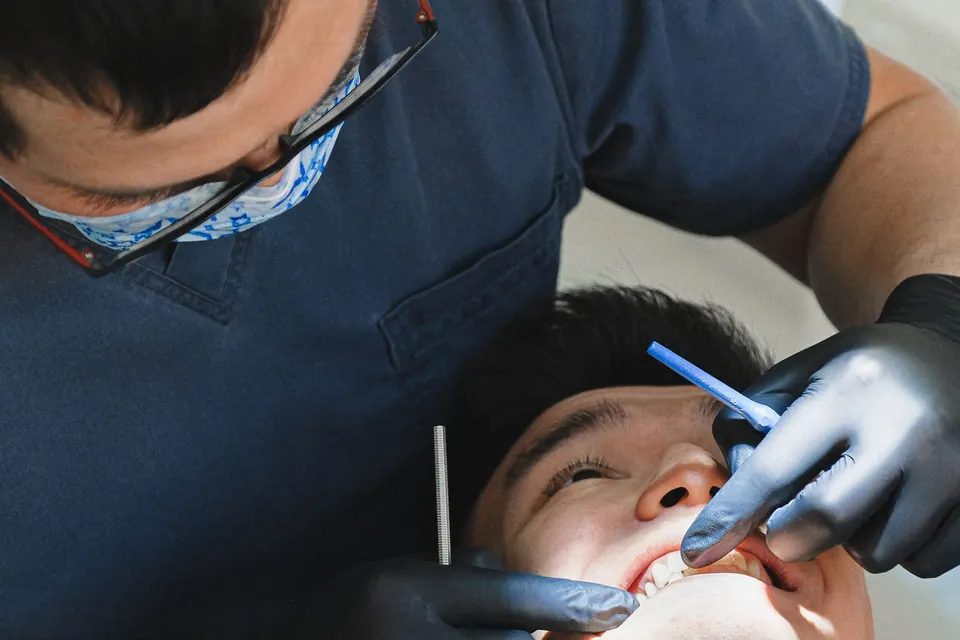 Dentist in a mask and gloves treating a patient in the dental chair