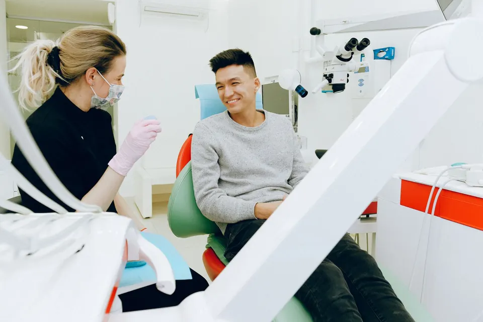 Dentist talking with a patient seated in a dental chair before treatment
