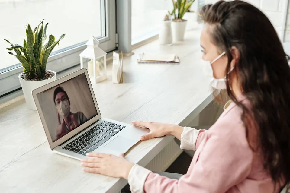 Woman on a video call with a doctor shown on a laptop screen