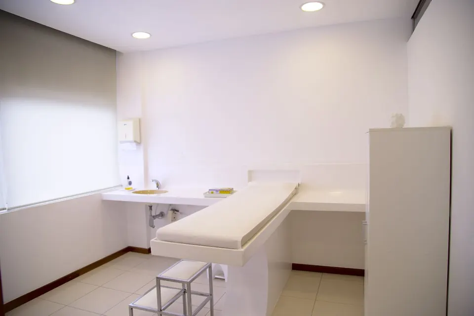 Clean, empty clinic examination room with a couch and sink