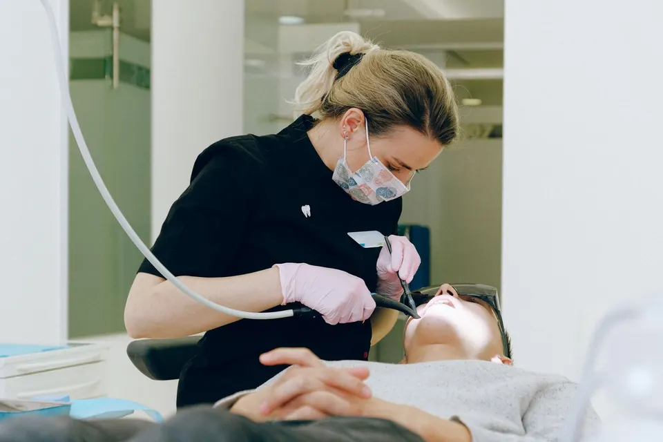 Dentist in a mask treating a patient lying in a dental chair